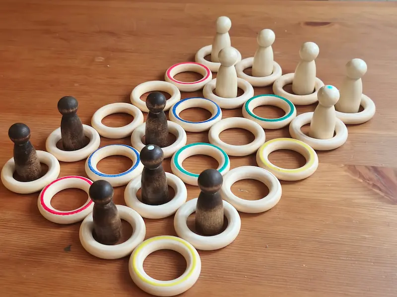Partida de Mosaiki en curso: anillos de madera de cinco colores y piezas torneadas sobre una mesa de madera